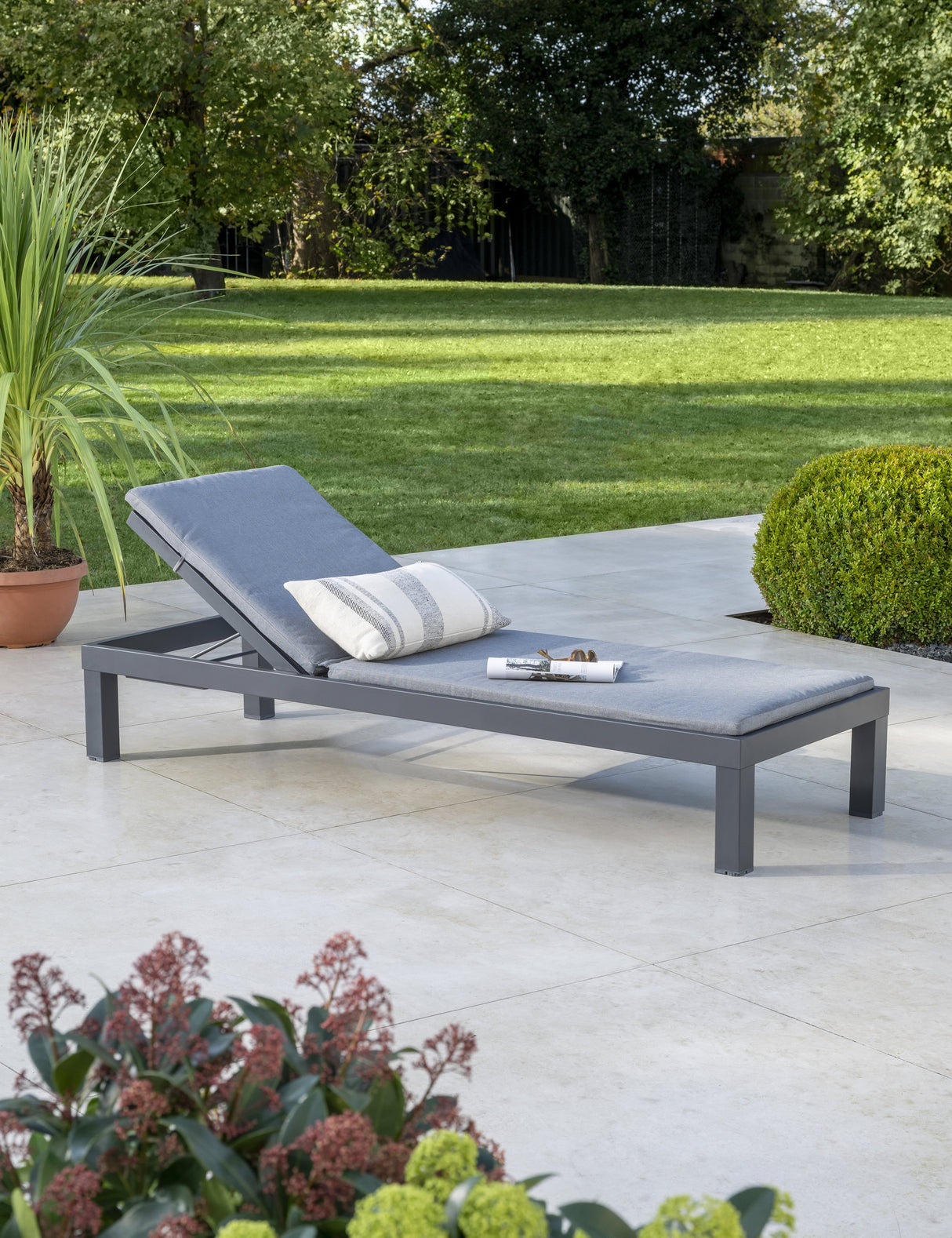 Kettler Elba Signature sun lounger in grey with cushion, metal outdoor furniture, shown in a relaxed outdoor setting.