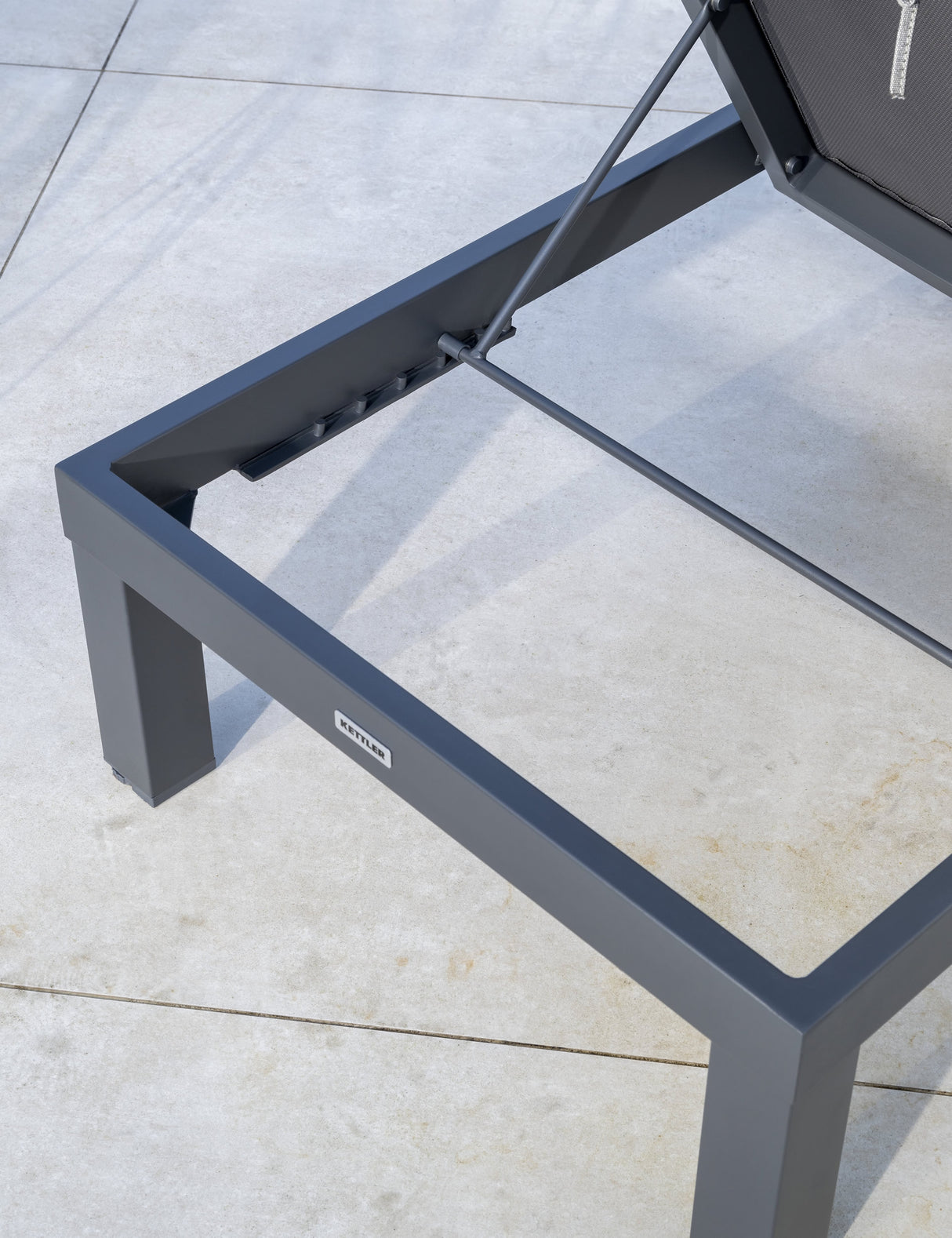 Kettler Elba Signature grey sun lounger with cushion, metal outdoor furniture, shown in a relaxed outdoor setting.