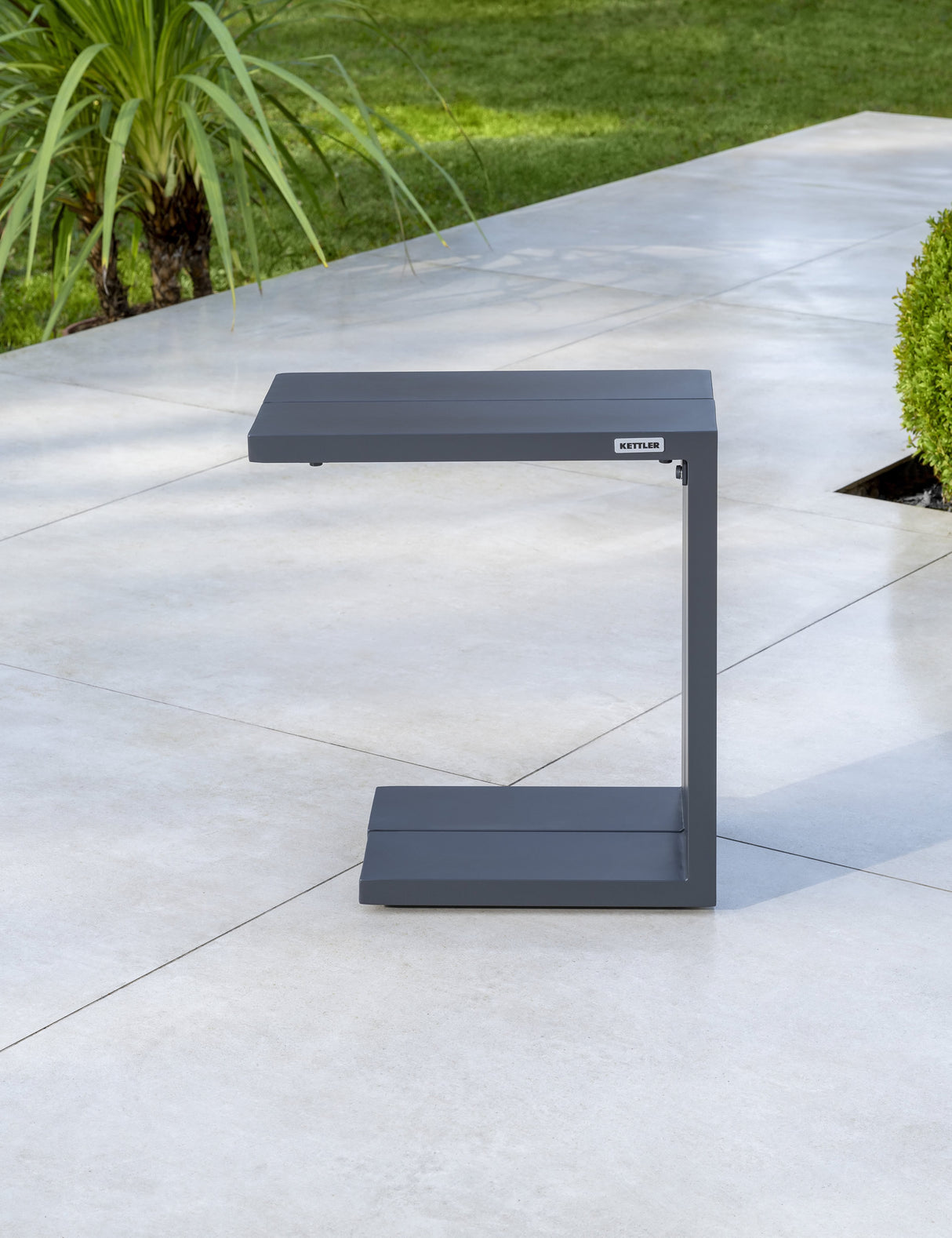 Kettler Elba grey metal side table shown in a lifestyle setting, featuring a sleek, modern design for outdoor or indoor use.