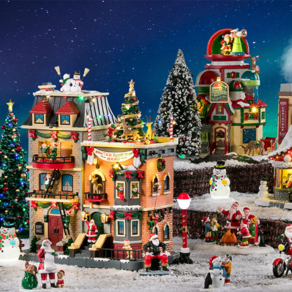 Christmas-themed model village with colorful buildings and decorations against a night sky.