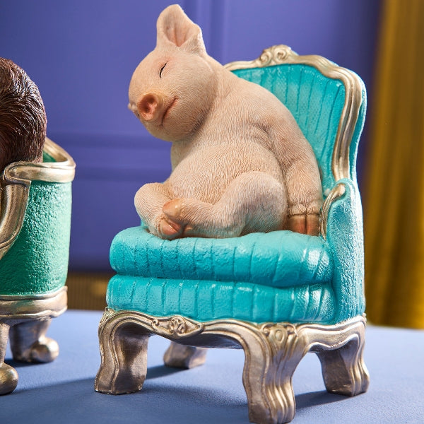 Werner Voß Snoozing Piglet ornament on green armchair, a 20cm luxury German designer figurine for home decor.