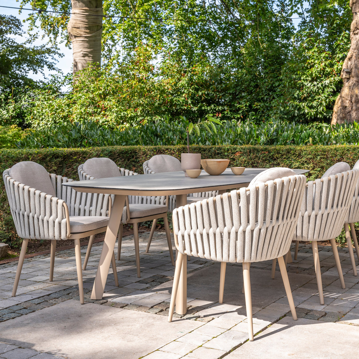 4 Seasons Outdoor Eva 6-seat metal dining set with Manolo 180cm barrel ceramic table and latte-colored dining chairs.